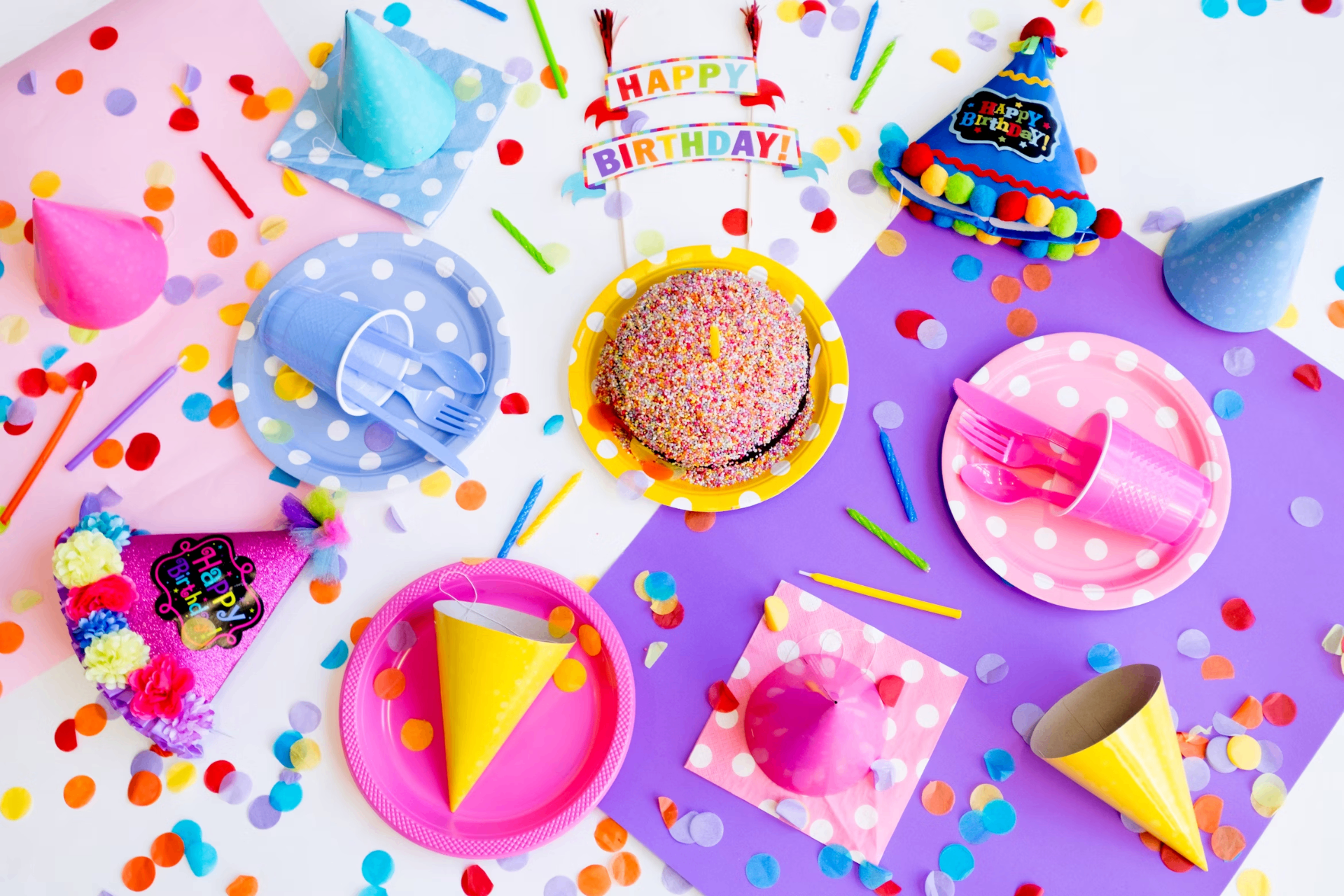 Kinderfeestje met kleurrijke bordjes, feesthoedjes en een taart